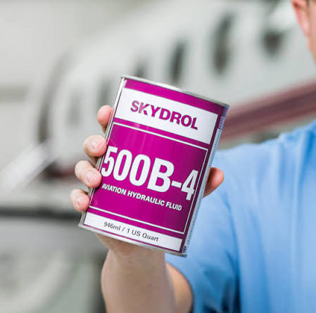 Technician holding a one-quart can of Skydrol 500B-4 aviation hydraulic fluid